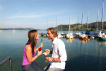 Pärchen beim Eisessen am Steg mit Booten im Hintergrund. See: Mattsee